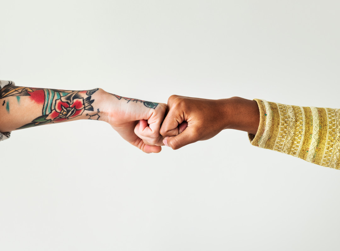 Two women bumping fists against a white background